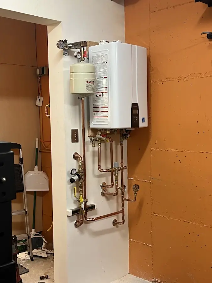 Plumbing technician inspecting water heater connections in Flat Rock